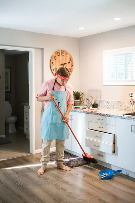 team-01 Pretty African American girl is mopping floor at home with flat plastic mop wearing gloves and wear-at-home clothing. Modern interiors, cleanness and young people concept.